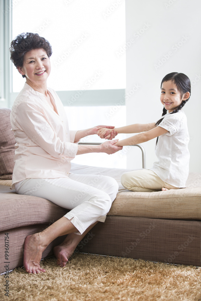 Happy grandmother and granddaughter playing in living room