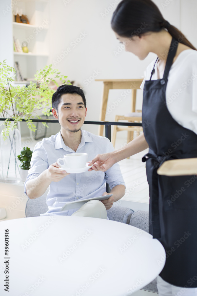 女服务员为年轻人端上一杯咖啡