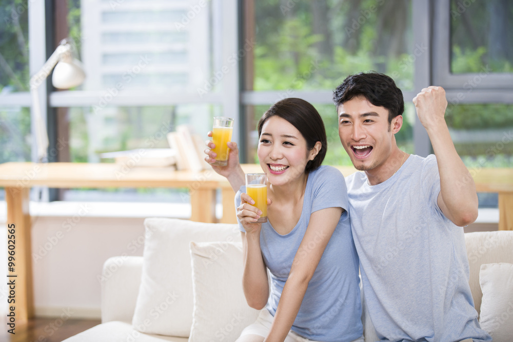 Young couple watching TV with orange juice