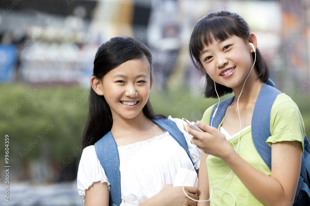 Schoolgirl playing smart phone with friend