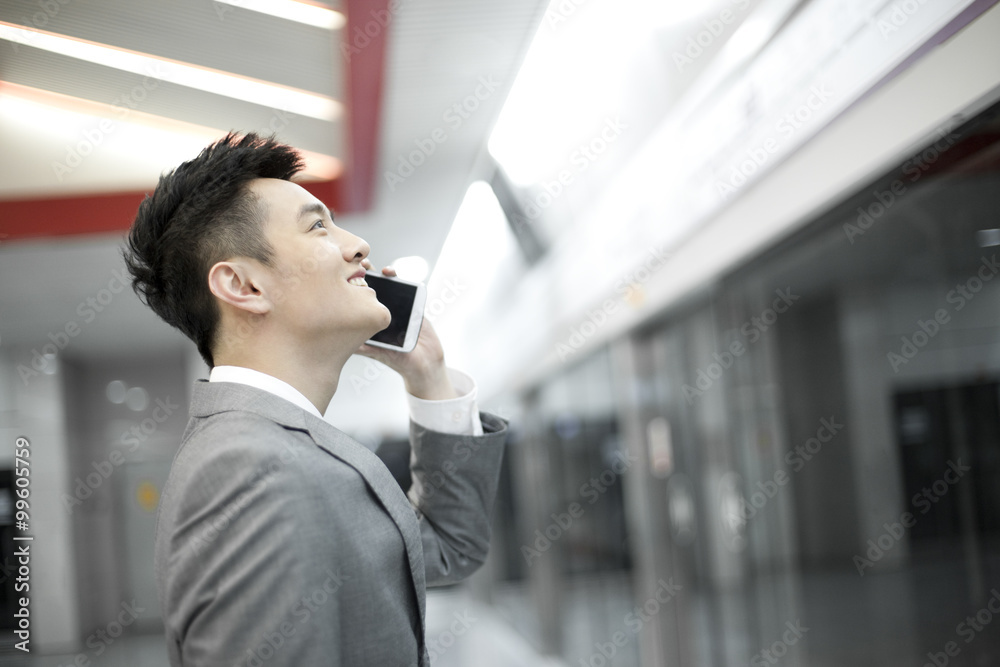 Young businessman on the phone on subway platform