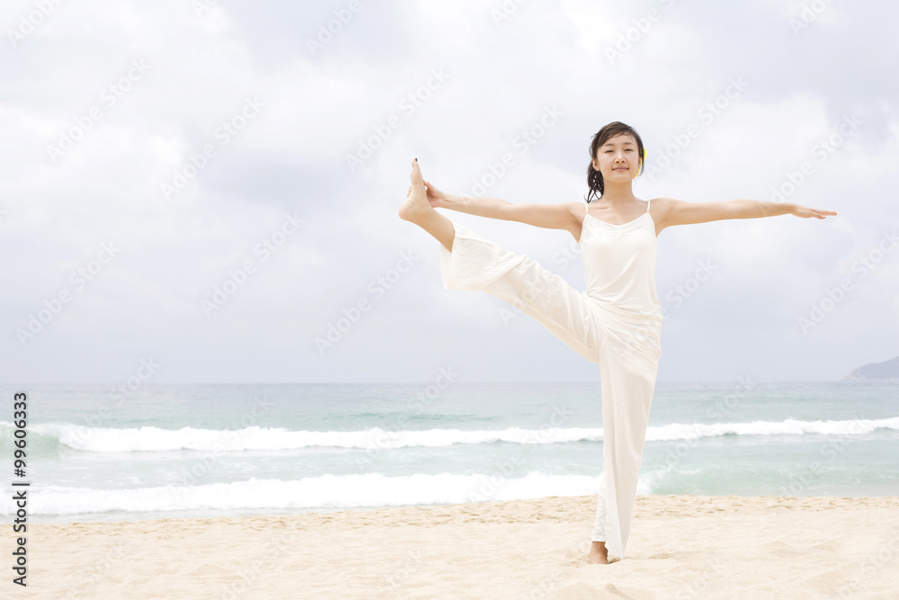 A woman practicing yoga at the beach