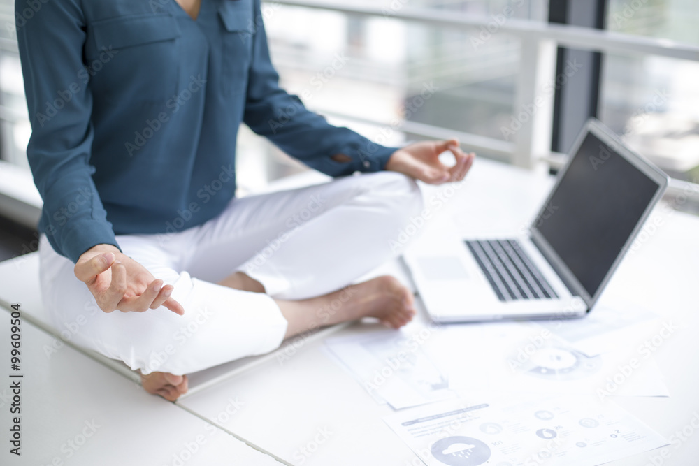 Young businesswoman doing yoga on office desk