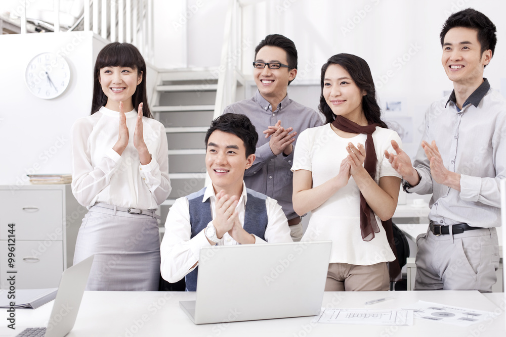 Happy office workers clapping in studio