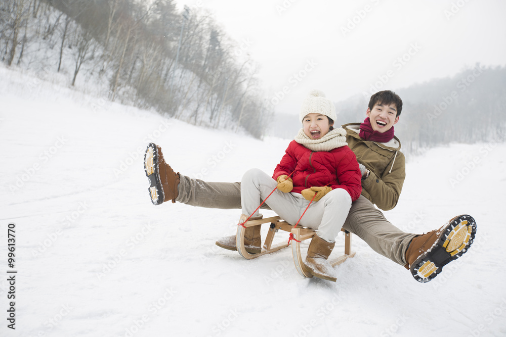 年轻的父女在雪橇上滑行