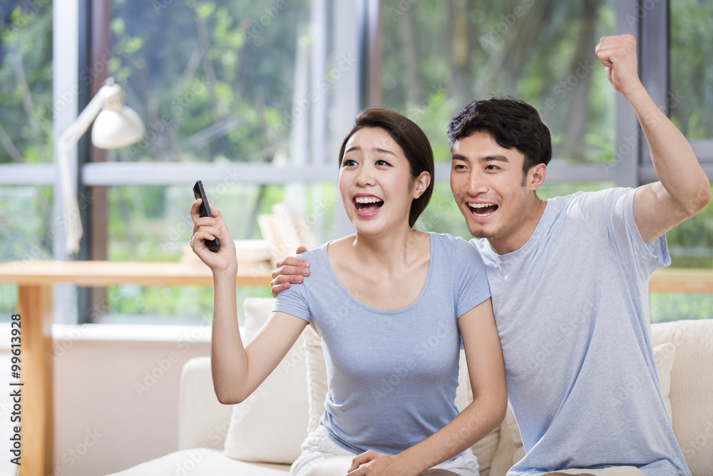 Excited young couple watching TV