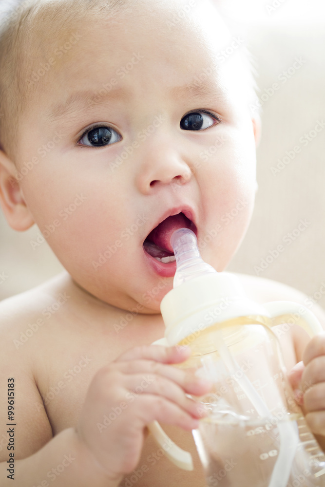 Cute baby boy drinking water from feeding bottle