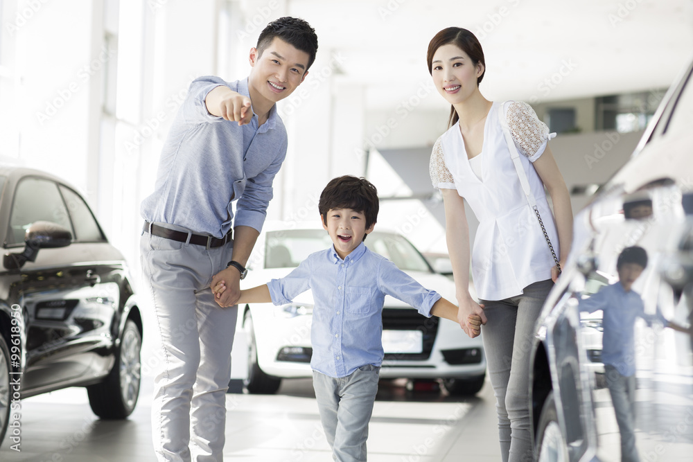 Young family looking at new car in showroom