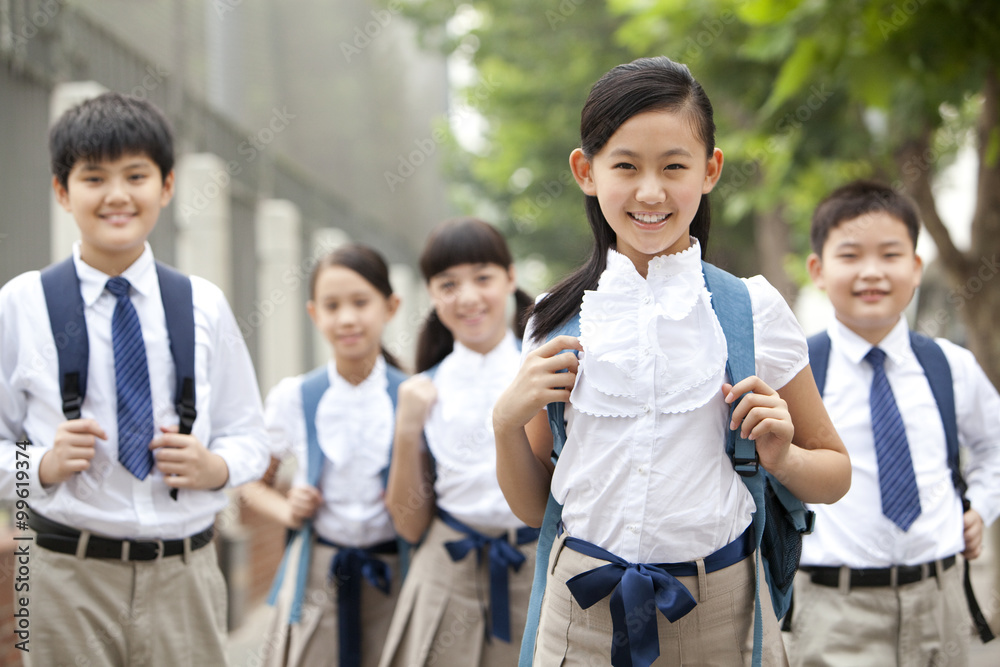 可爱的穿着制服的小学生在上学的路上