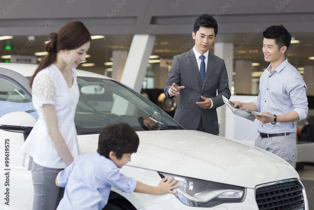 Young family choosing car in showroom