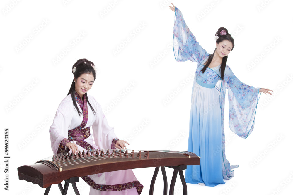 Young women in Chinese traditional costume plucking Chinese zither and dancing