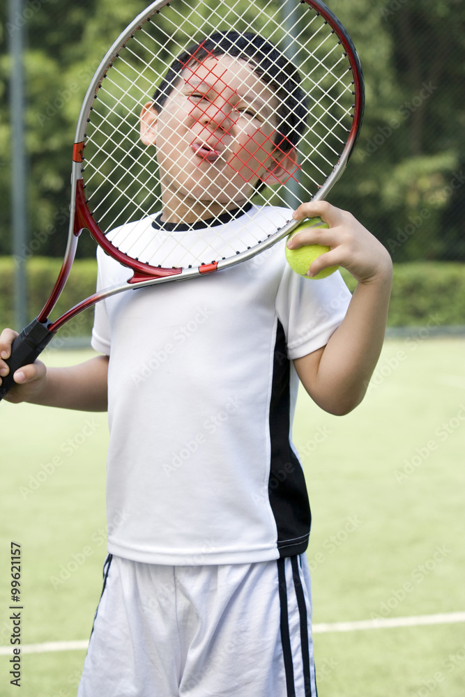 Funny portrait of a young boy on the tennis court