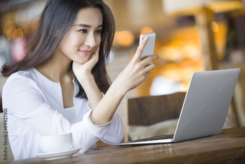 Young woman using smart phone in cafe