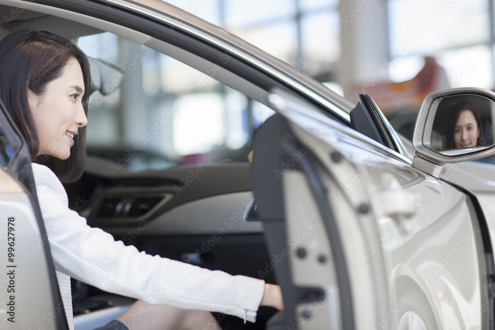 Young woman choosing car in showroom