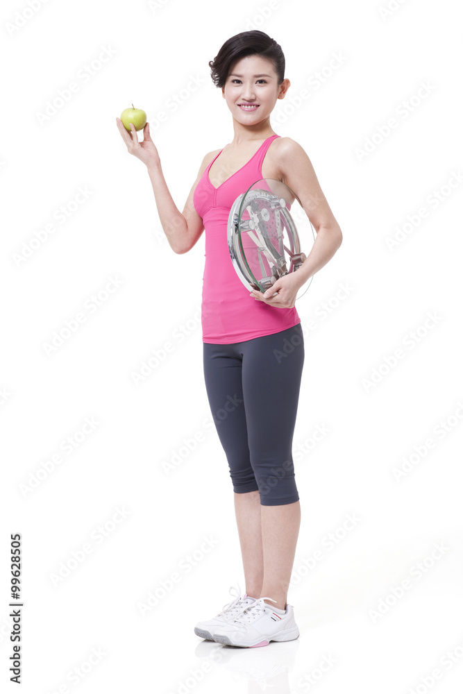 Slim young woman with apple and bathroom scale