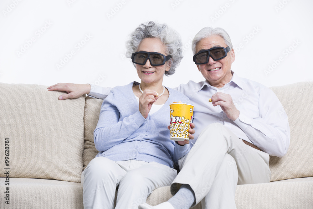 Senior couple watching 3D movie in living room