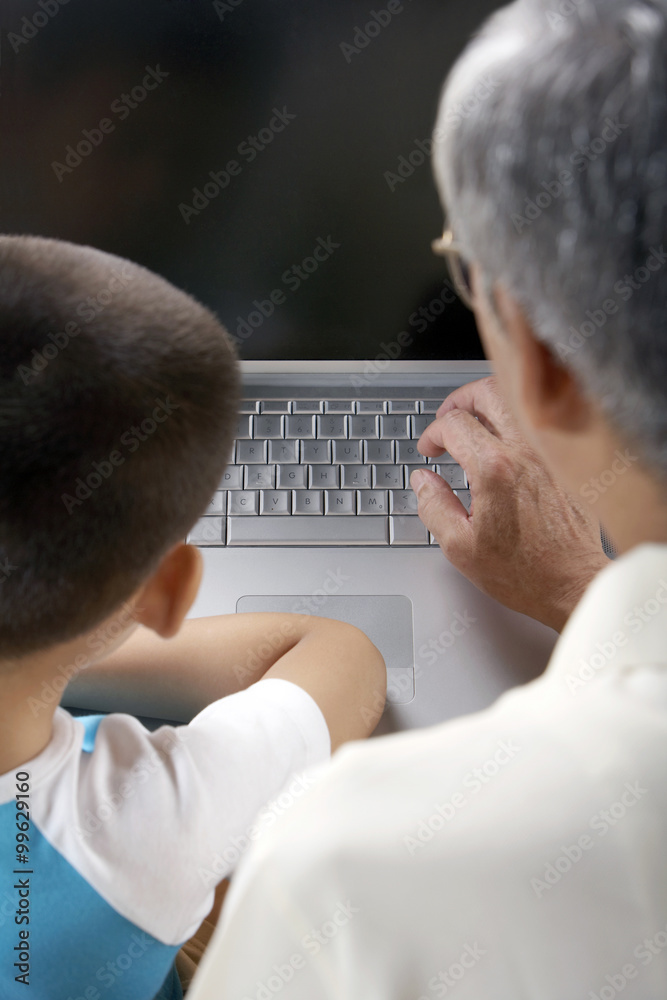 Elderly Man And Young Boy Using A Computer Together