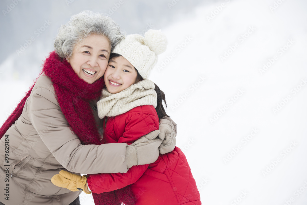 Happy grandmother and granddaughter embracing on the snow