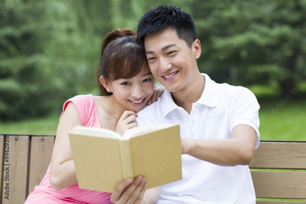 Young couple reading book in park