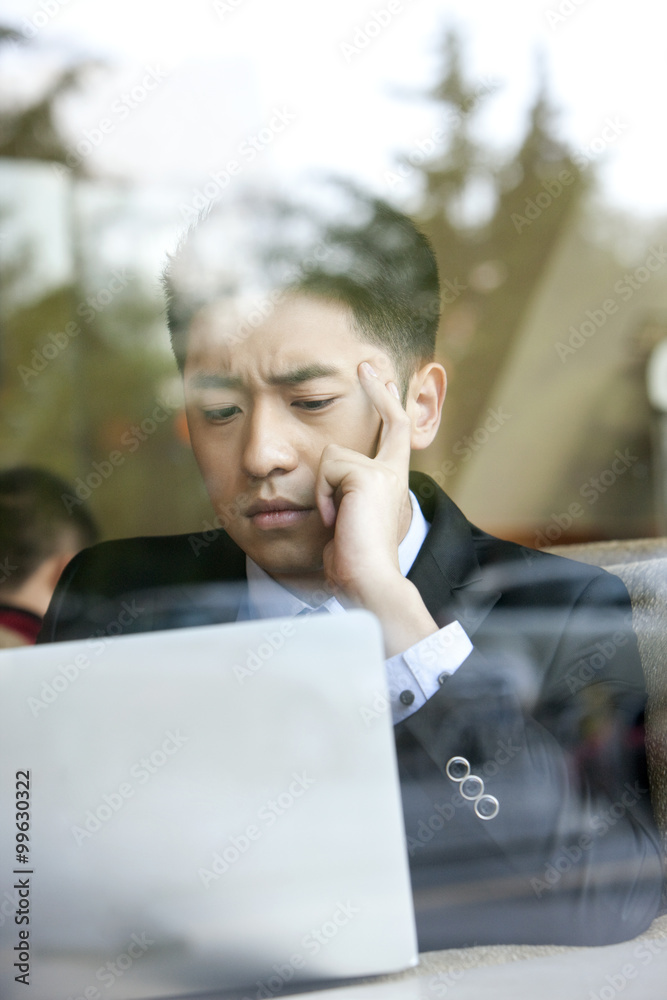 Serious businessman  using laptop in cafe