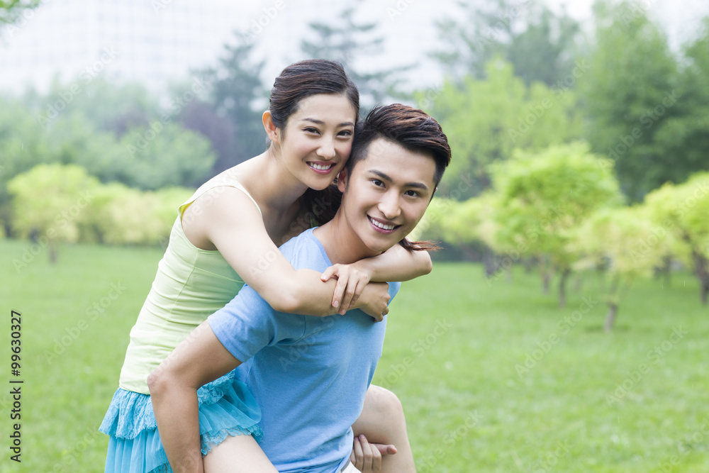 Young man giving her girlfriend a piggy back ride