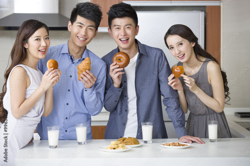 Happy young friends eating breakfast in the kitchen