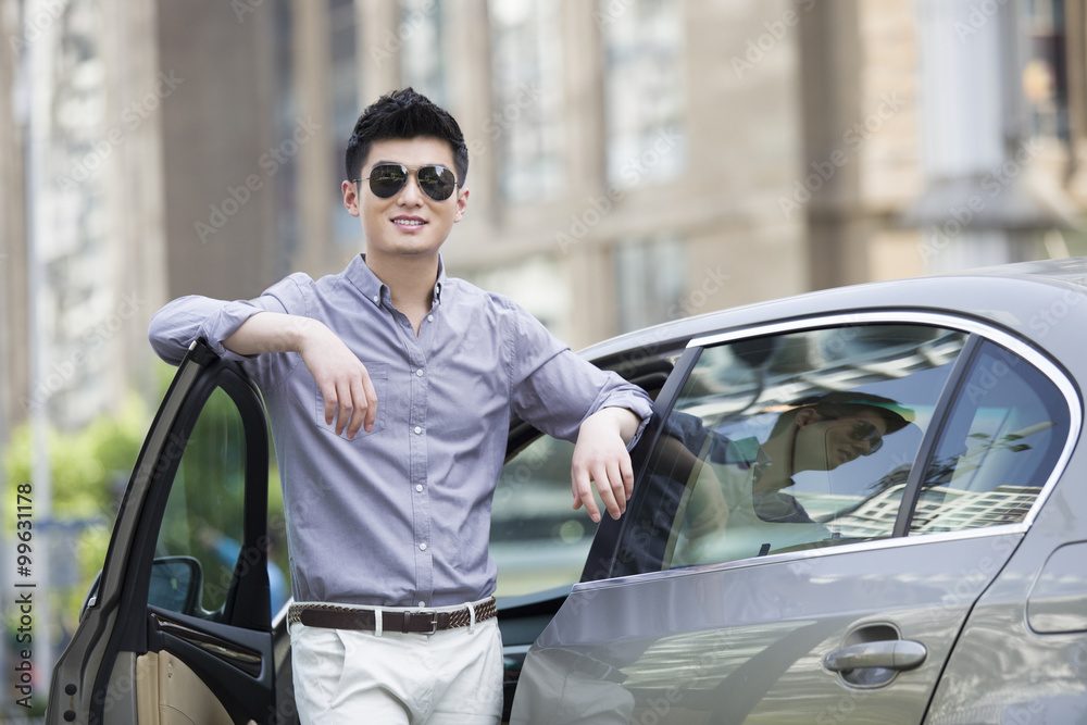 Young man standing next to his car