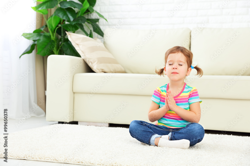 child little girl meditates in lotus position and practices yoga