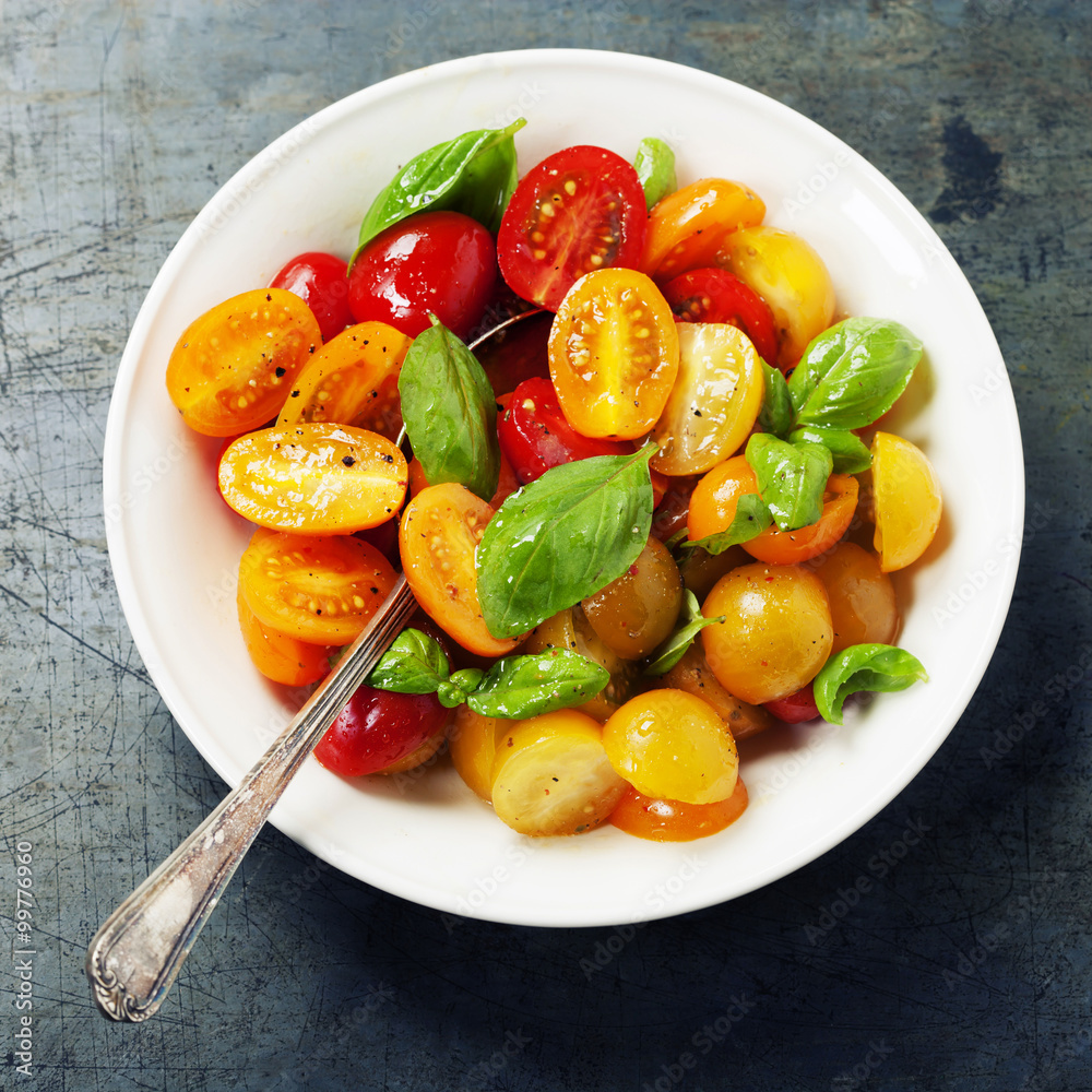 Fresh tomatoes with basil leaves in a bowl