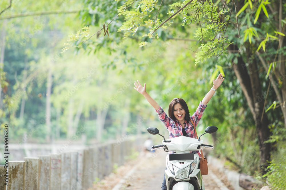 年轻的亚洲女子在公园里骑摩托车