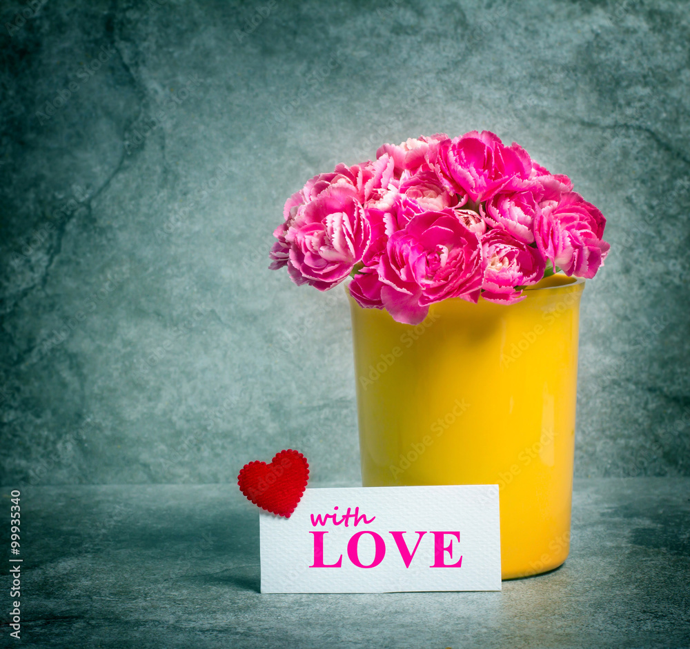 Fresh pink carnation flower and love card over stone plate 