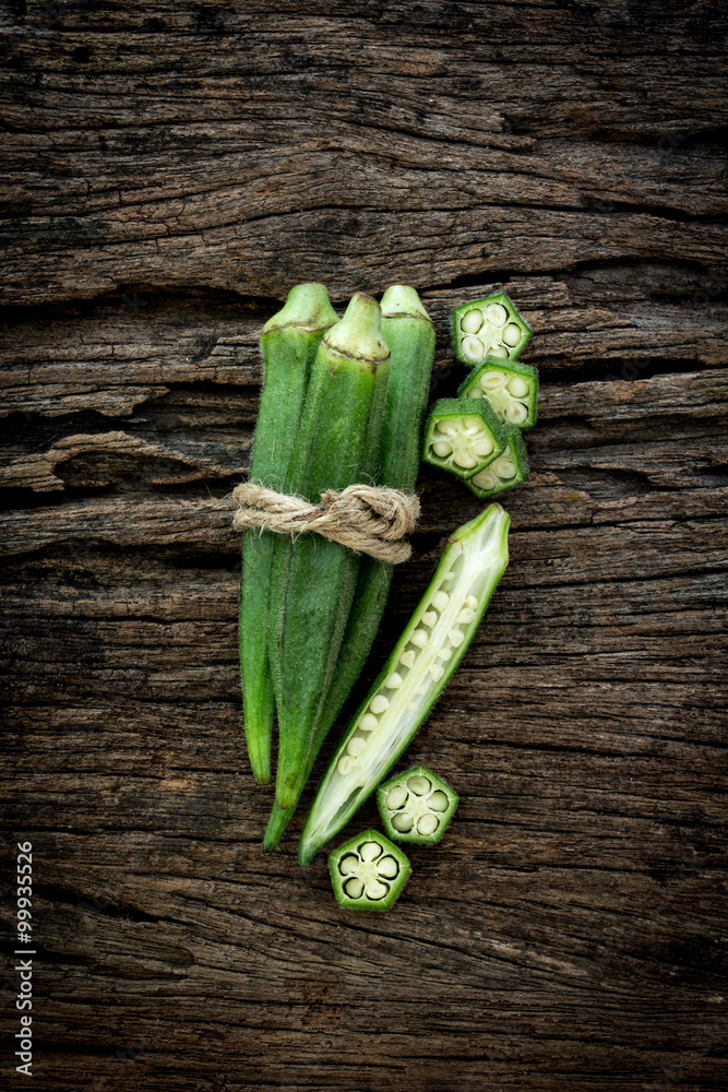 Close up fresh okra on wooden plate , overhead shot