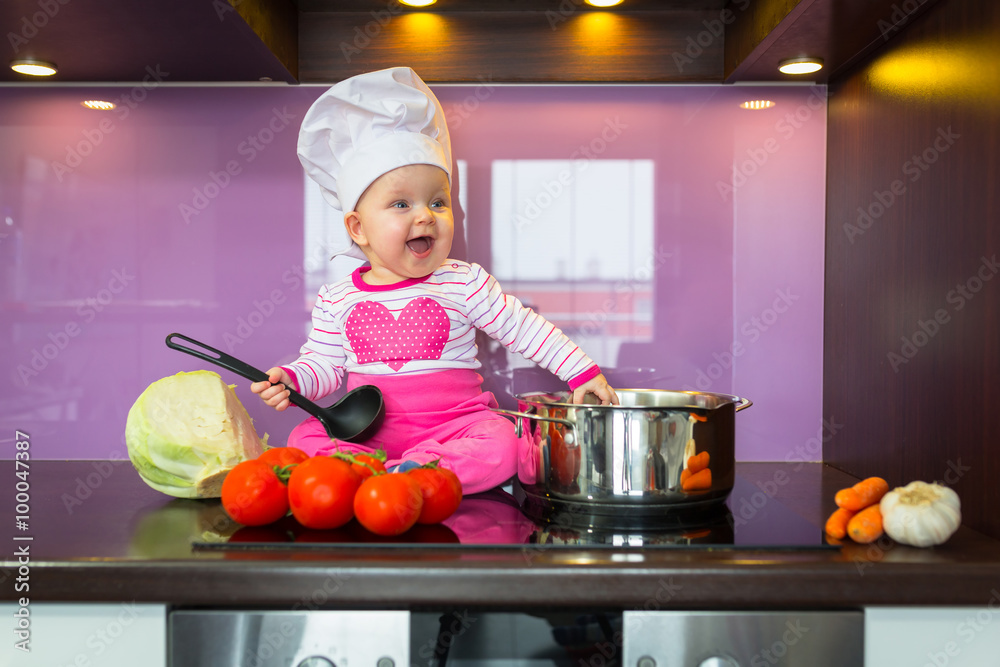 Little baby girl cook in chef hat at the kitchen