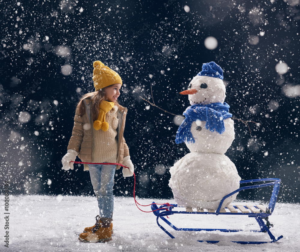 girl plaing with a snowman