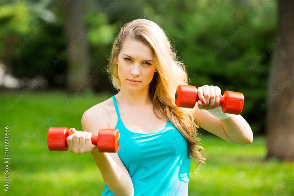 Sports girl exercise with  dumbbells in the park