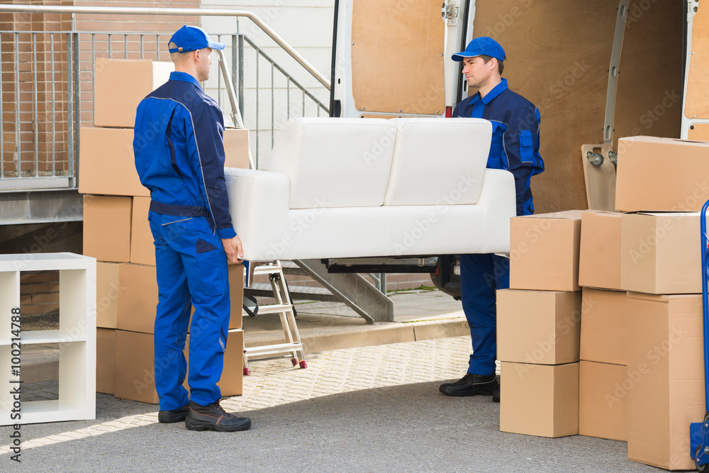 Movers Carrying Sofa Outside Truck On Street