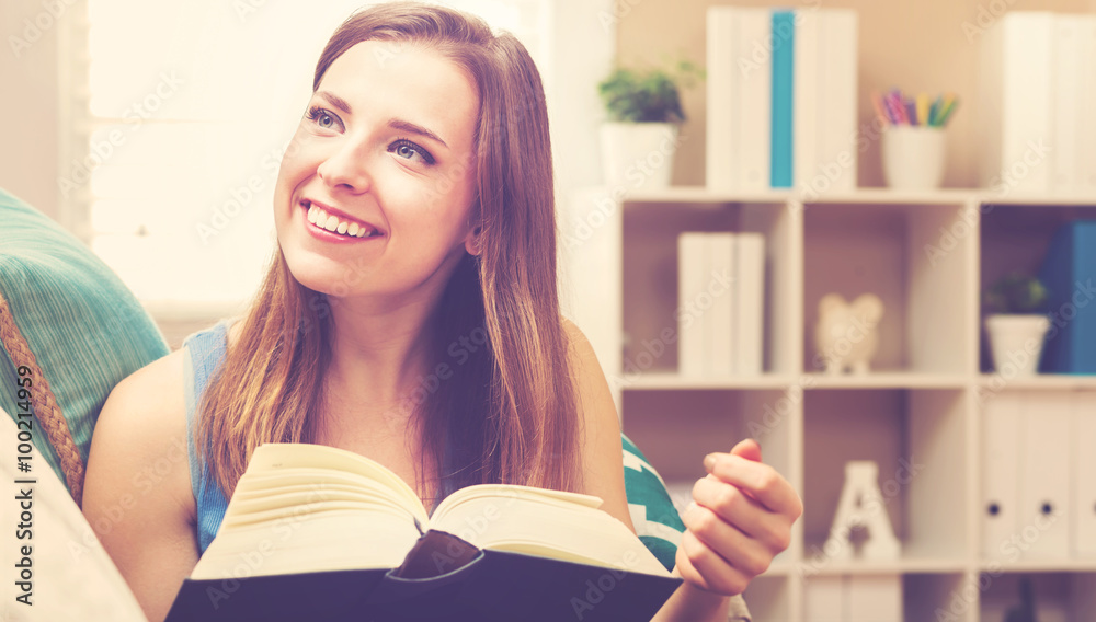 Happy young woman reading a book