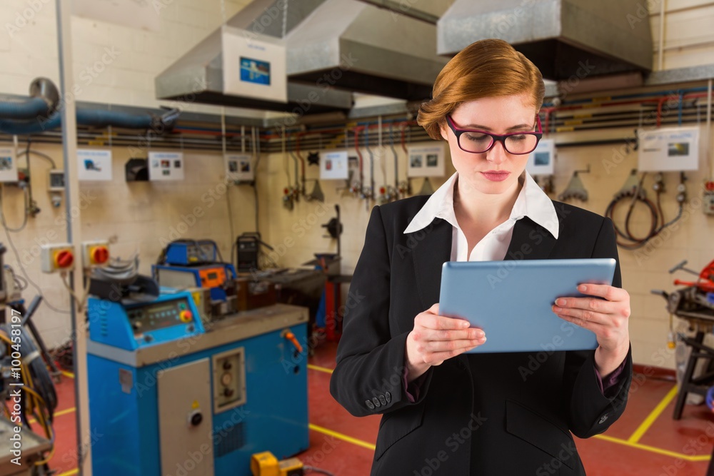 Composite image of redhead businesswoman using her tablet pc