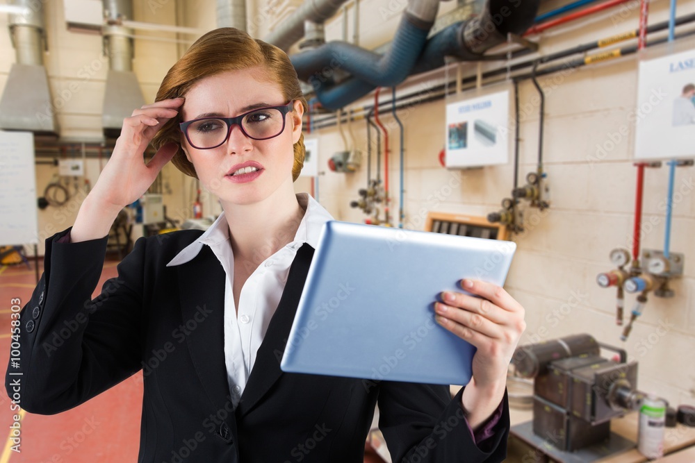 Composite image of redhead businesswoman using her tablet pc