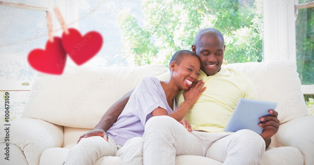 Composite image of happy smiling couple using laptop on couch