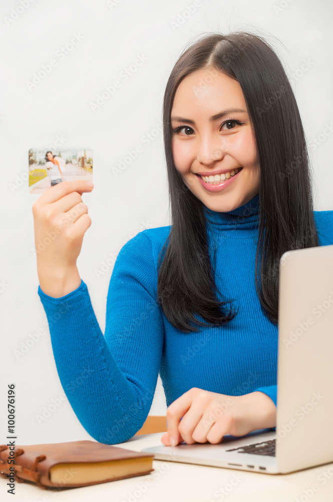 亚洲女人微笑着，手里拿着她的信用卡。