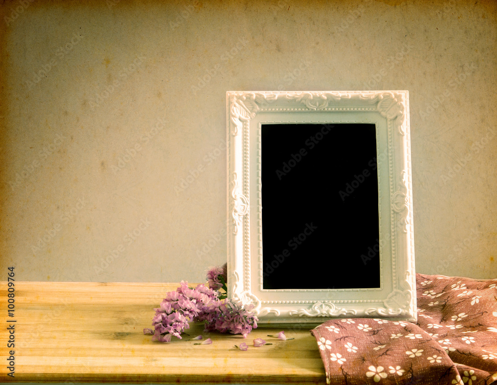 White vintage photo frame with sweet  flower on  wooden table