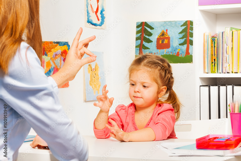 Preschooler playing hand game with teacher