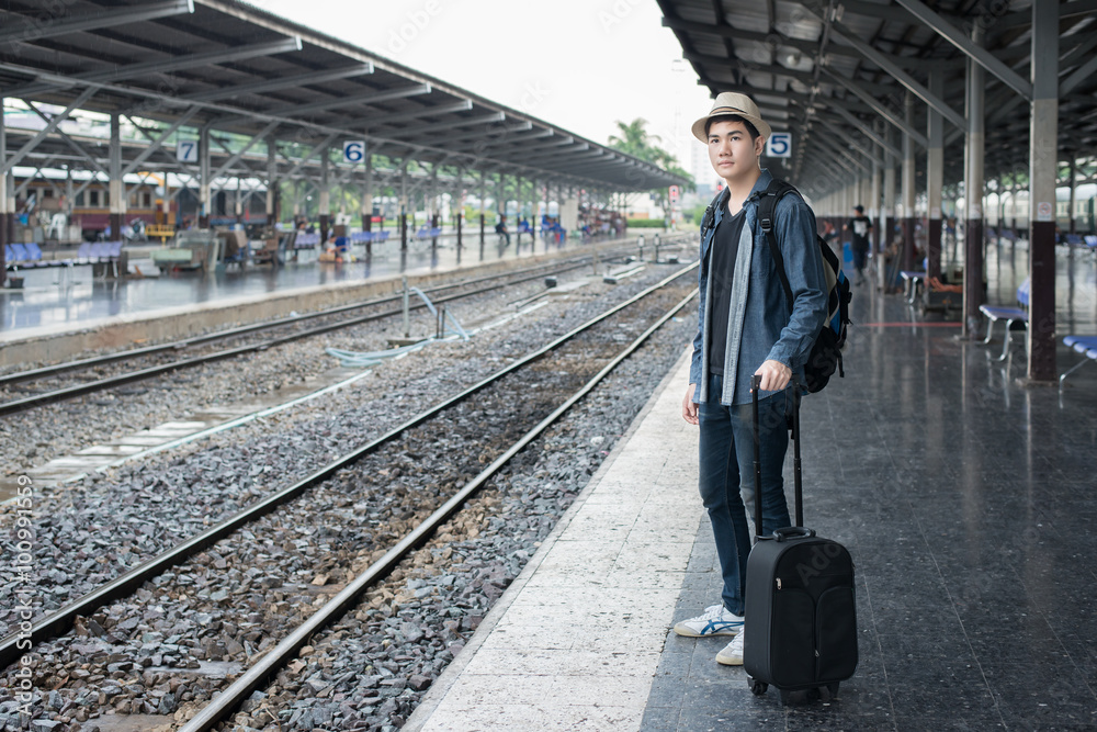 Asian young man waiting train for journey at station