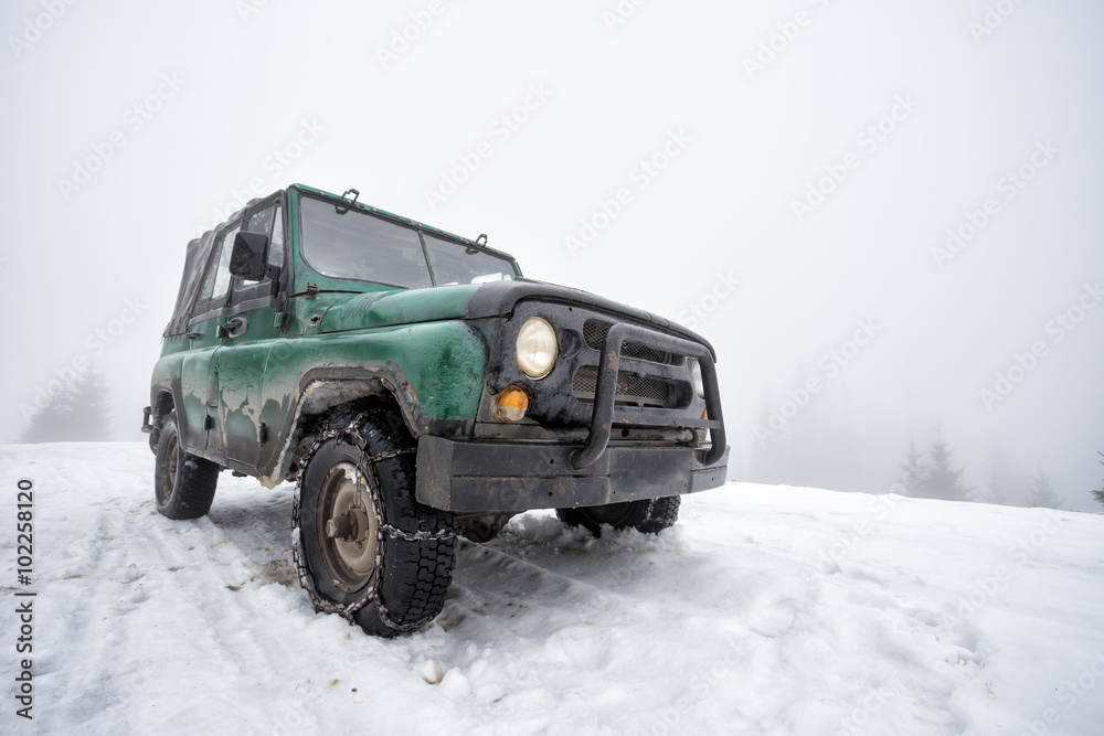 雪山上的绿色老式越野车