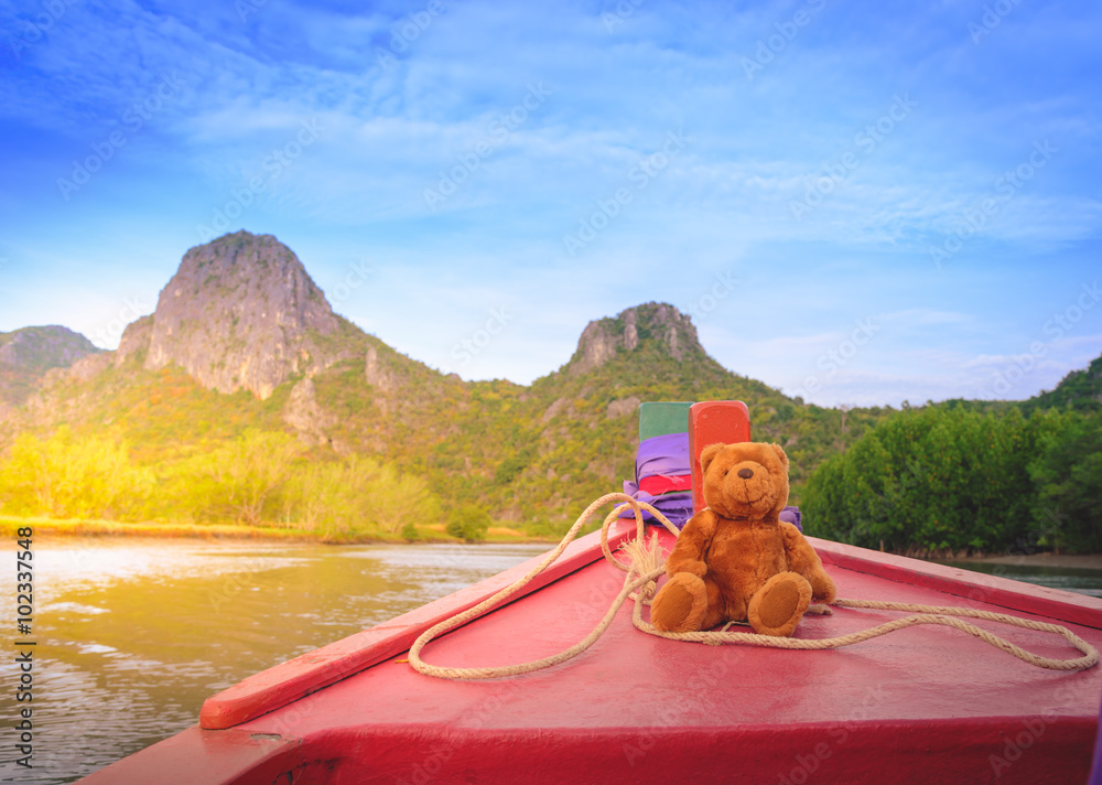 Teddy bear on the Old red boat in countryside. Vintage tone.