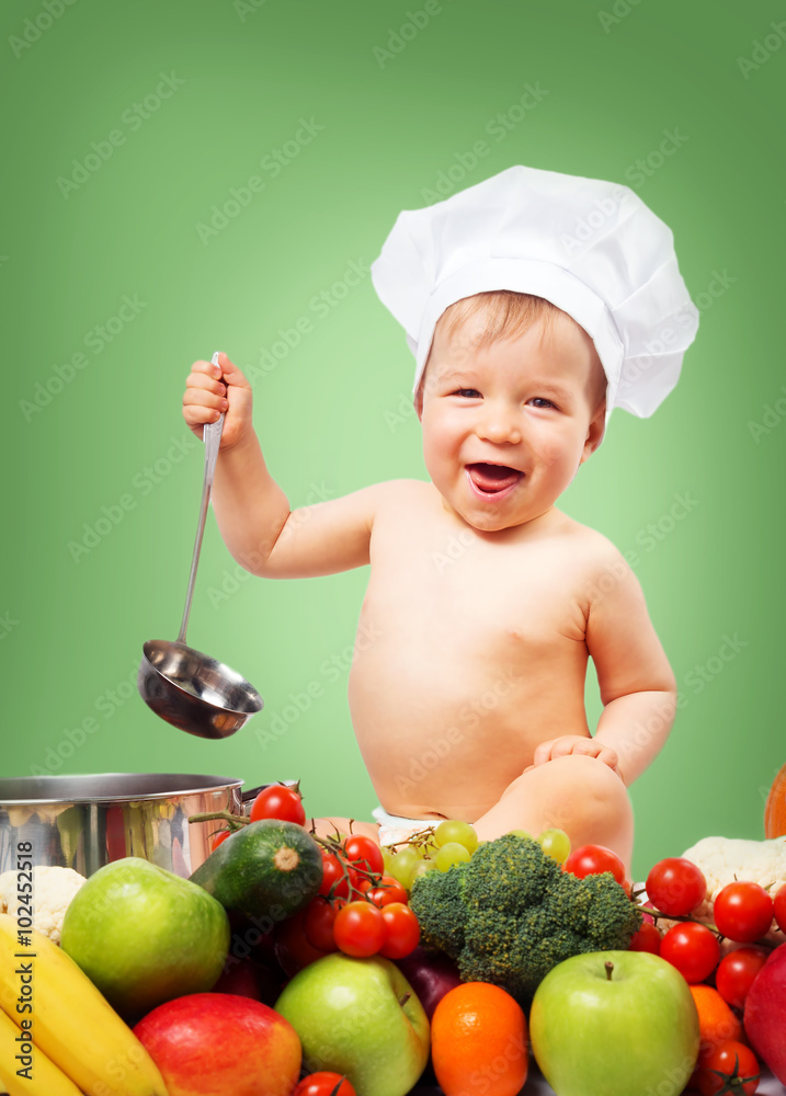 Baby boy in chef hat with cooking pan and vegetables