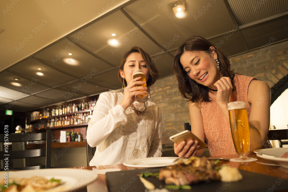 两个女人一边喝啤酒一边在餐厅用餐