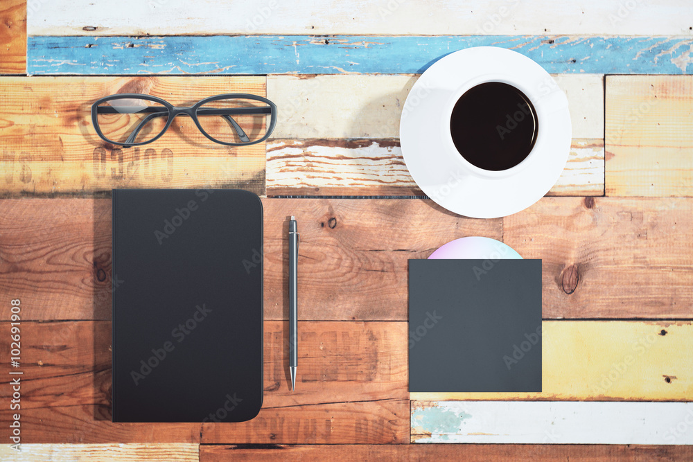 Black cover of diary, cup of coffee, pen and CD disk on multicol