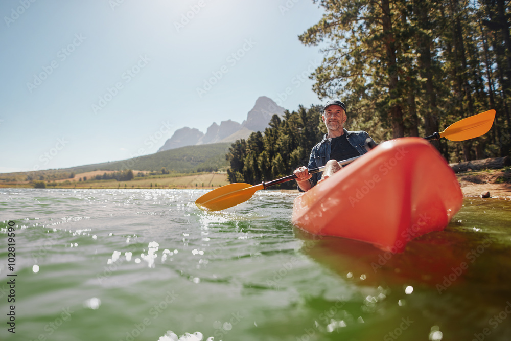 Senior man canoeing in a lake on a sunny day